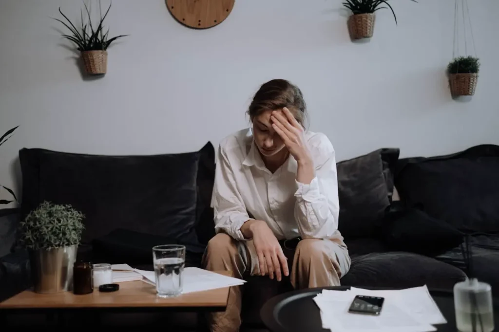 Frau sitzt auf einer Couch, den Kopf in eine Hand gestützt