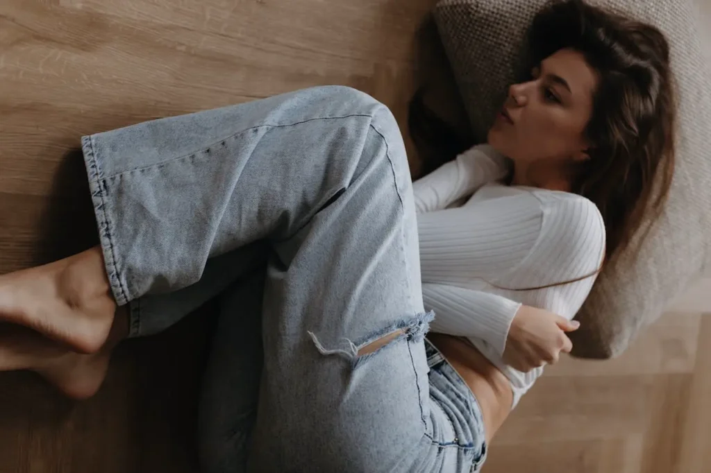 Frau liegt auf dem Boden und umarmt sich selbst