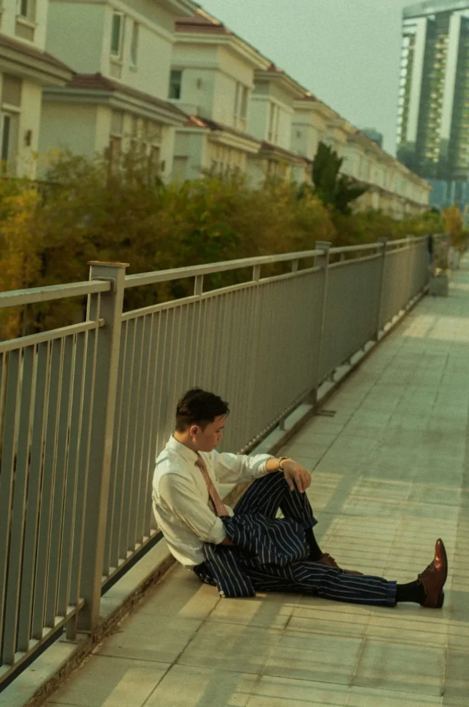 Mann im Anzug sitzt an ein Geländer gelehnt auf dem Boden