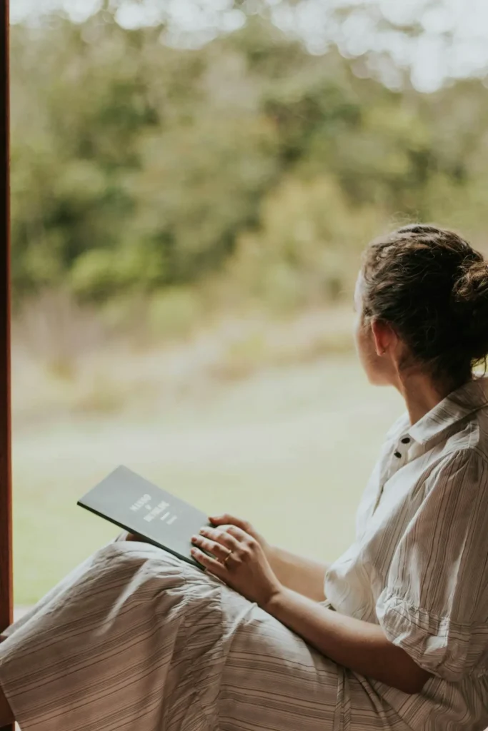 Frau sitzt mit einer Mappe in der Hand am Fenster