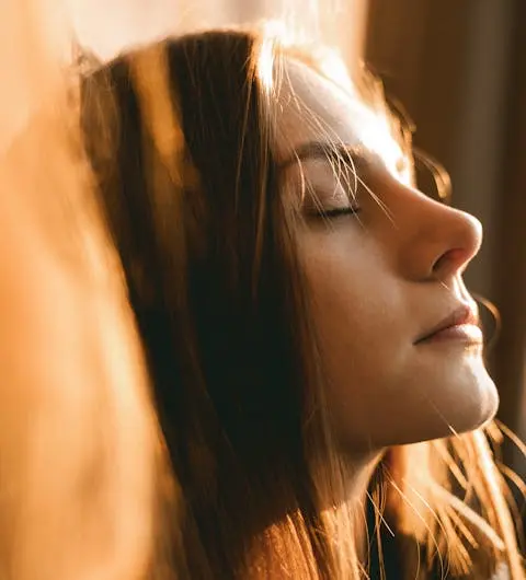 Frau mit geschlossenen Augen und Sonne im Gesicht