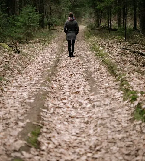 Person steht auf einem herbstlichen Waldweg