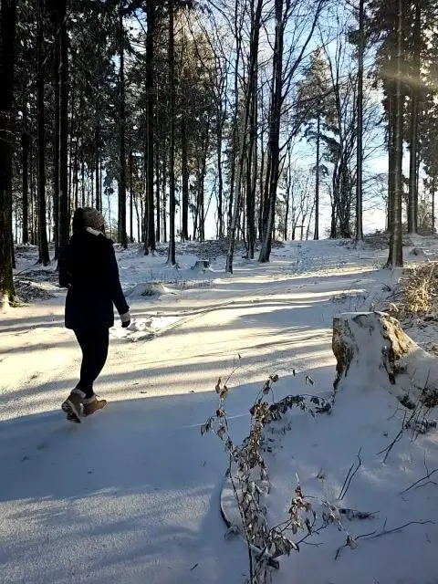 Frau läuft auf schneebedecktem Waldweg